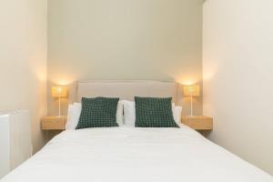 1 dormitorio con cama blanca y almohadas verdes en Bonito apartamento en Sol, en Madrid