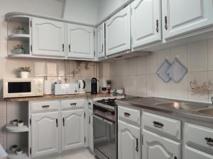 una cocina blanca con armarios blancos y fregadero en Blue Boat House - The Atlantic Breeze, en Nazaré