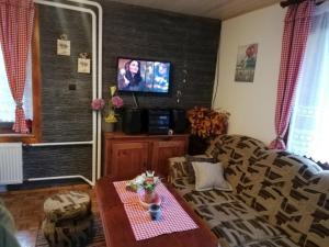a living room with a couch and a tv at Chata na Čertove in Štôla