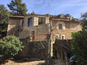 une maison en pierre avec un balcon sur un mur en pierre dans l'établissement La Bergerie Pradel, à Le Beaucet