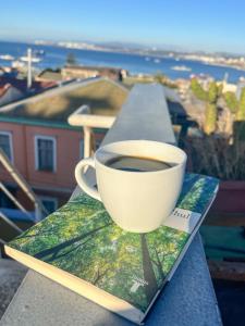 uma chávena de café sentada num livro na varanda em Lemuria Hostel em Valparaíso