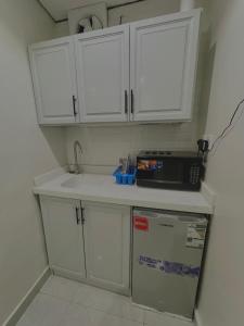 eine Küche mit weißen Schränken, einer Spüle und einer Mikrowelle in der Unterkunft استديو مع جلسة خارجية بدخول ذكي in Riad