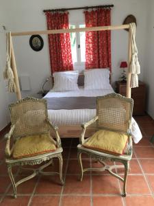 a bedroom with a bed and two chairs at La Bergerie Pradel in Le Beaucet