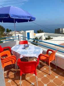 een tafel en stoelen op een balkon met een parasol bij Awechtam house in Aouchtame