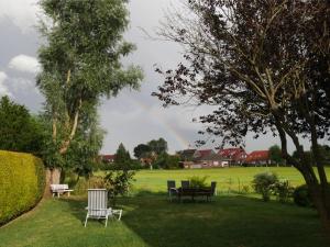 un arc-en-ciel dans un champ avec bancs et tables dans l'établissement Ferienwohnung Backbord, à Werdum