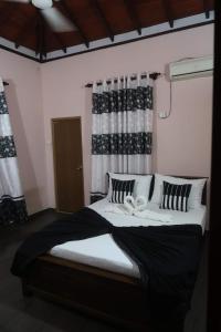 a bedroom with a large bed with black and white pillows at Airport Villa D 87 in Katunayaka