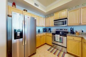 a kitchen with wooden cabinets and a stainless steel refrigerator at Holiday Isle 413 in Dauphin Island