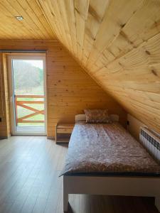 een bed in een houten kamer met een groot raam bij Sielankowe Pole in Józefów