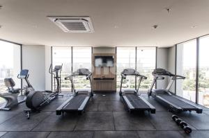 un gimnasio con máquinas de correr, TV y ventanas en Luxurious And Dazzling Villa Morra Apartment, en Asunción