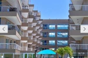 a large apartment building with balconies and an umbrella at Condomínio Beach Place Cumbuco in Caucaia