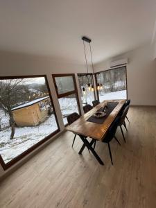 uma sala de jantar com uma mesa de madeira e janelas grandes em Biutiful Bungalow em Vişeu de Sus