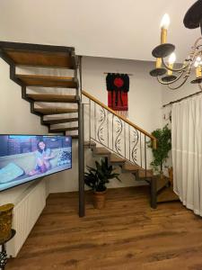 a living room with a staircase and a flat screen tv at Apartament Yannis in Alba Iulia