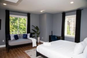 a bedroom with a bed and a couch and two windows at Lux Stay by Center City/Temple in Philadelphia