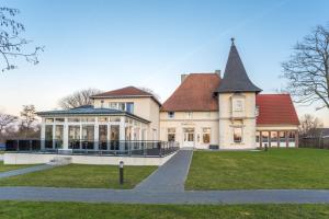 Una gran casa blanca con un salón acristalado en un césped en Hotel Bloemfontein en Borkum