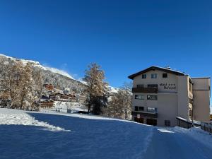 un parcheggio coperto di neve di fronte a un edificio di Hotel Belmont a Crans-Montana