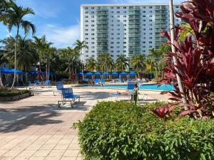 uma piscina com cadeiras azuis e um edifício alto em Sunny Isles Condo Resort em Miami Beach