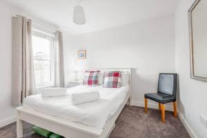 a white bedroom with a bed and a chair at Pitmilly Park - 3 Beds - Garden in Kingsbarns