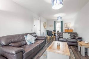 a living room with a leather couch and a table at Pitmilly Park - 3 Beds - Garden in Kingsbarns