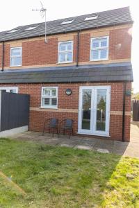 a brick house with two chairs on a patio at Private room in a new build in Heanor