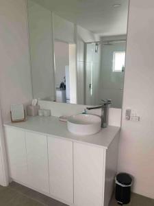 a white bathroom with a sink and a mirror at Tequila Sunset in Yamba