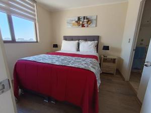 um quarto com uma cama grande e um cobertor vermelho em Departamento Mirador Camilo Henriquez em Concepción