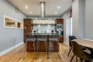 a kitchen with a bar with chairs and a table at Pipeland Loft, Central, Parking in St. Andrews