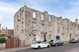 a large brick building with two cars parked in front of it at Pipeland Loft in St. Andrews