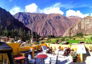 un balcón con mesas y sillas con montañas en el fondo en Casa Samay Mountain View, en Ollantaytambo