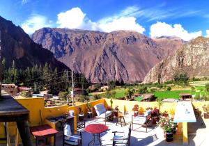 a balcony with tables and chairs with mountains in the background at Casa Samay Mountain View in Ollantaytambo