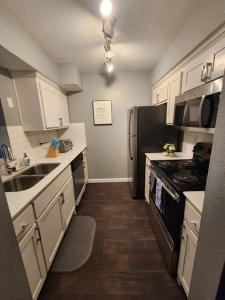 a kitchen with white cabinets and a black refrigerator at Blue Shark *B542* @ Medical Center Modern 1BR King Apartment in Houston