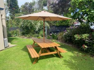 einen hölzernen Picknicktisch mit einem Sonnenschirm im Hof in der Unterkunft The Ground Floor Guest Suite in Dunedin