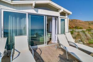 a porch with white chairs and sliding glass doors at Beachfront Malibu Apartment with Ocean-View Balcony in Malibu