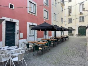 une rangée de tables et de chaises avec parasols dans une rue dans l'établissement Contemporary Apartment in Chiado 3, à Lisbonne