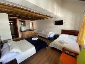 a bedroom with two beds and a tv on the wall at Muisca Hotel Villa de Leyva in Villa de Leyva