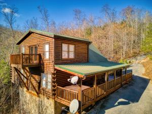 eine Blockhütte im Wald mit einem grünen Dach in der Unterkunft Heavenly Bear, Hot Tub, FREE Attraction tickets for each paid day, Pool Table, WIFI!!! in Sevierville