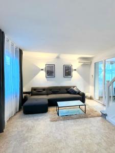 een woonkamer met een zwarte bank en een tafel bij Maison Entier JO 2024 Clim Disney 2 rooms in Gournay-sur-Marne