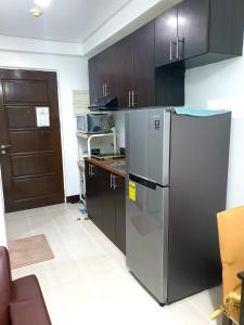 una cucina con frigorifero in acciaio inossidabile e mobili in legno di Studio Unit Persimmon Condominium a Cebu City