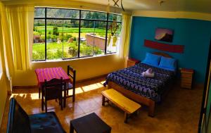 a bedroom with a bed and a table and a window at Casa Samay Mountain View in Ollantaytambo