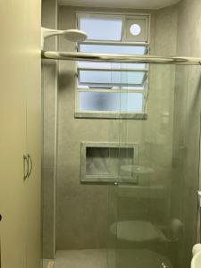 una puerta de ducha de cristal en un baño con ventana en Flat Copacabana quadra da praia 907, en Río de Janeiro