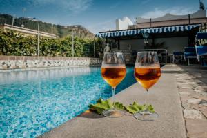 two glasses of wine sitting next to a swimming pool at Hotel Casa Giuseppina in Ischia