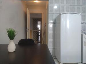 a kitchen with a refrigerator and a table with a vase at Apto 348 centro nucleo bandeirante in Núcleo Bandeirante