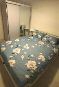 een bed met een blauwe deken met witte bloemen erop bij Apartman MiSSS in Pale