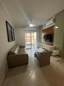 a living room with a couch and a tv at Apartamento Praia Grande 405 in Ubatuba