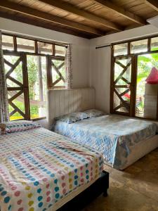 two beds in a bedroom with two windows at Finca Mi Carmencita in Mocoa