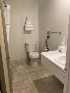 a bathroom with a toilet and a sink and towels at Travelodge by Wyndham Canyonville in Canyonville