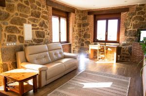 sala de estar con sofá y pared de piedra en La Tahona, en Fermoselle