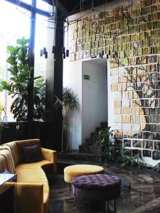 a lobby with a couch and chairs and a brick wall at Ikonik Hotel Puebla in Puebla
