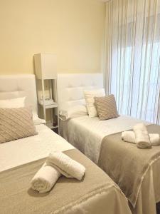 een slaapkamer met 2 bedden en handdoeken bij Apartamento Playa Blanca in Corcubión
