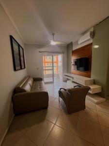 a living room with a couch and a tv at Apartamento Praia Grande 405 in Ubatuba