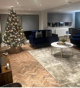 una sala de estar con un árbol de Navidad y un sofá azul en The Coach House at Wenvoe Manor, Cardiff, en Wenvoe